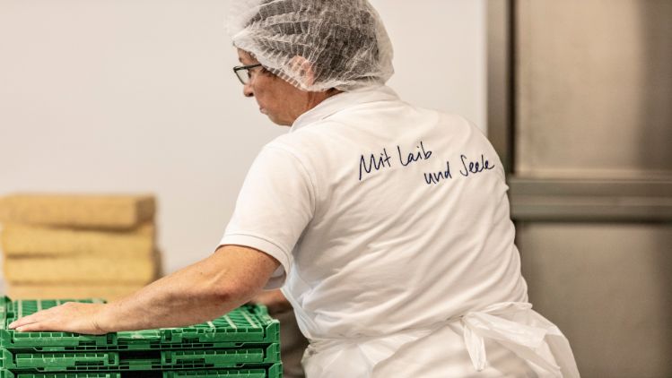 Das Bild zeigt eine Mitarbeiterin in der ChäsChuchi beim Transportieren von Käse. Baumann Käse verarbeitet und konfektioniert die Käse weiter.