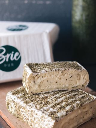 Kräuterbrie mit Kräutern im Teig und auf der Oberfläche.